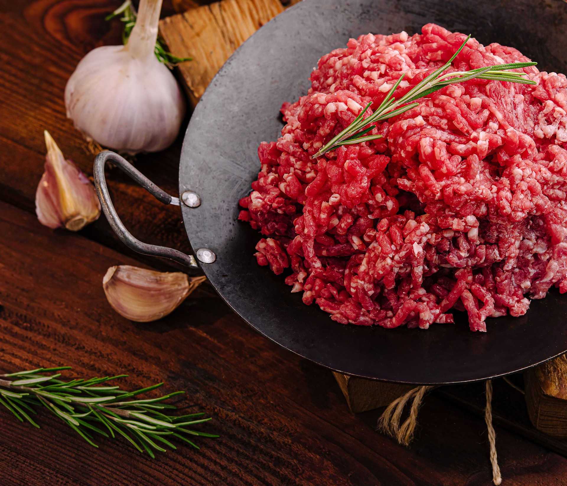 Fresh ground beef with herbs and vegetables on rustic wooden table